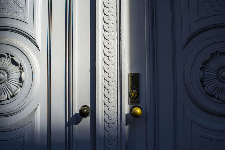 Full frame shot of closed white decorated door lit by sunlight