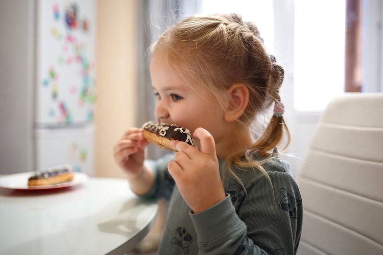 Cute girl eating doughnuts at home