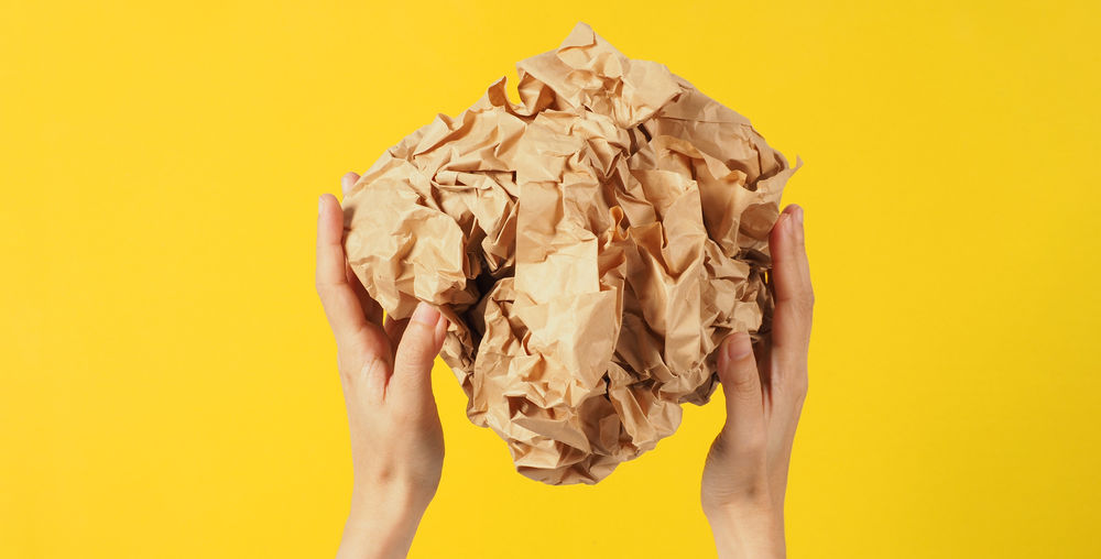 Low section of woman holding seashell against yellow background