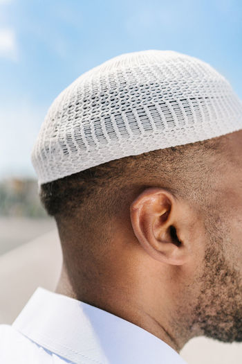 Anonymous islamic male in authentic knitted headgear standing on blurred background on sunny summer day