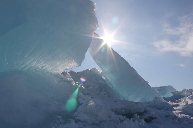 Low angle view of snowcapped ice shards draped in sunlight against a clear sky