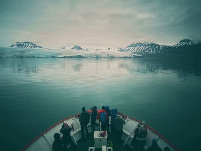 People riding in boat on lake against sky
