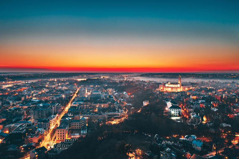Aerial view of illuminated cityscape against sky during sunset