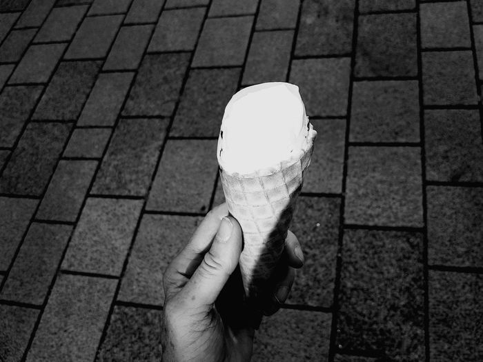 Person holding ice cream on footpath
