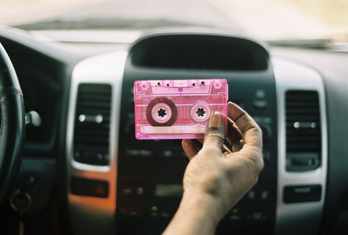 Cropped hand of person holding audio cassette in car