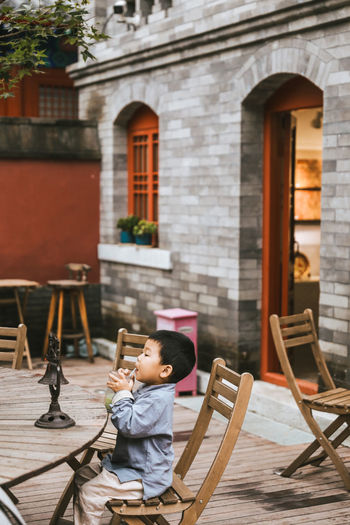 Boy sitting on chair outside building