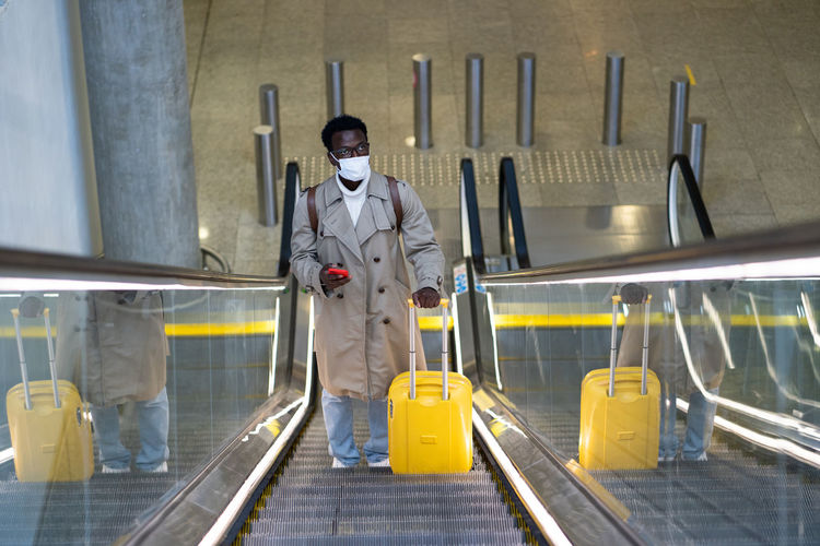 Side view of toy man wearing mask standing on escalator