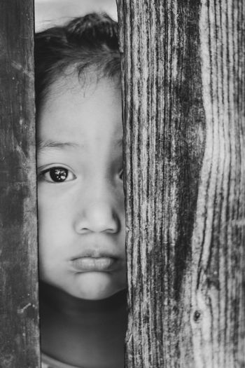 Close-up portrait of girl peeking through fence