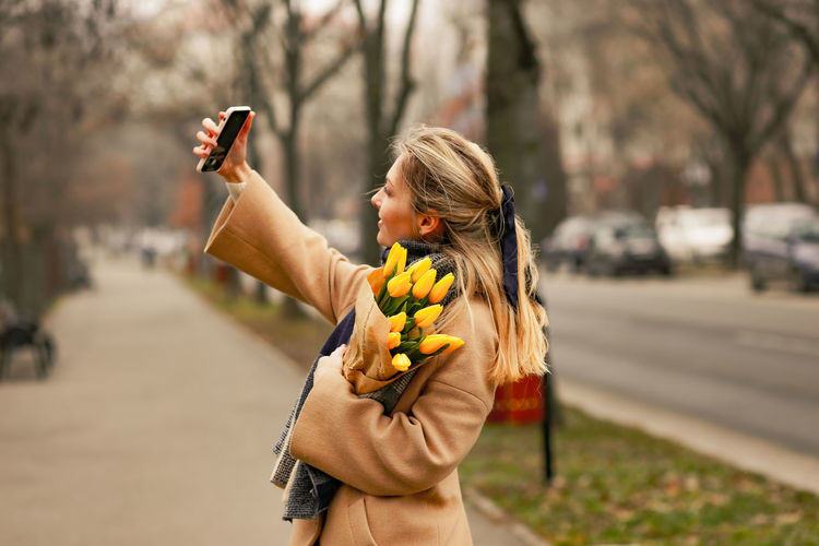 Young woman using mobile phone while standing in city