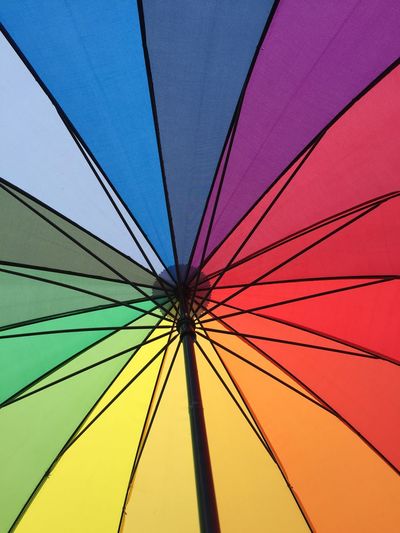 Low angle view of multi colored umbrella against clear blue sky