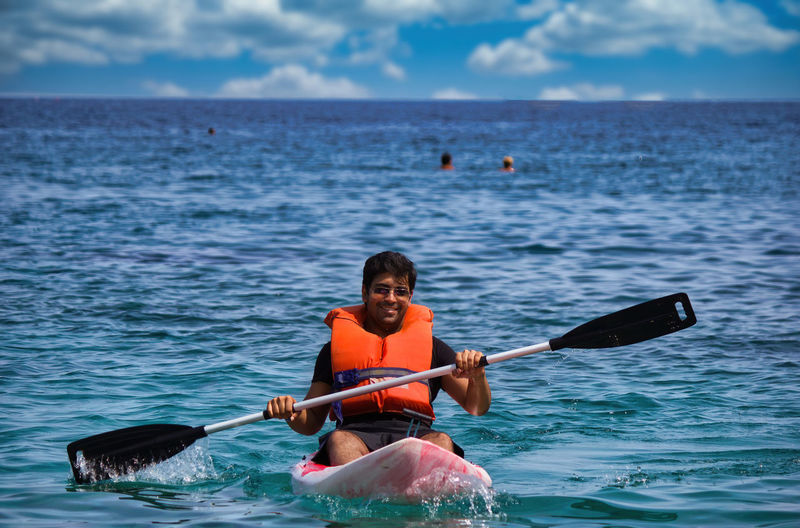 Crete, greece - man in life jacket floating and paddling on a kayak in sea. water sport kayaking