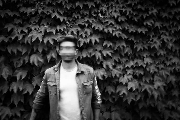 Portrait of young man standing against wall