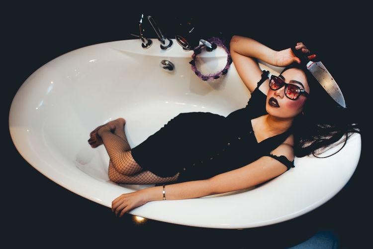 Full length portrait of young woman with knife in bathtub
