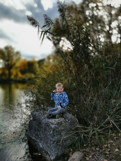 Boy on rock by tree
