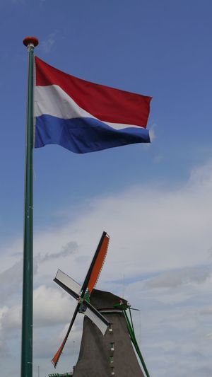 Low angle view of flag of netherlands and windmill against sky