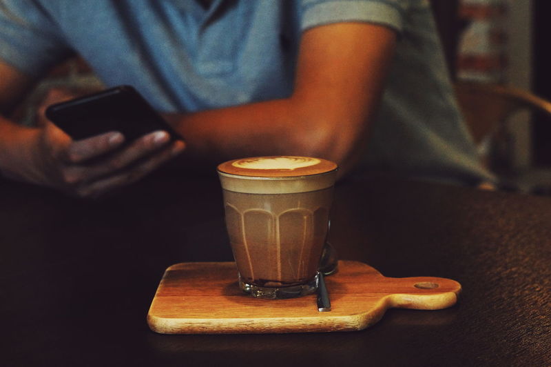 Midsection of man holding coffee cup on table