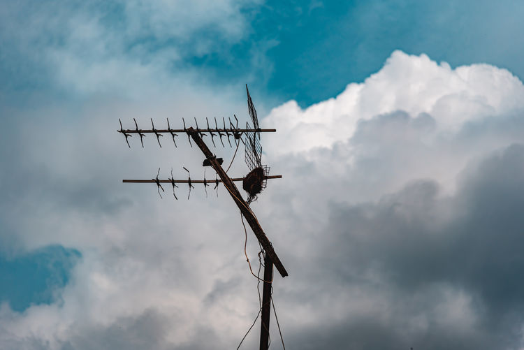 Low angle view of silhouette communications tower against sky