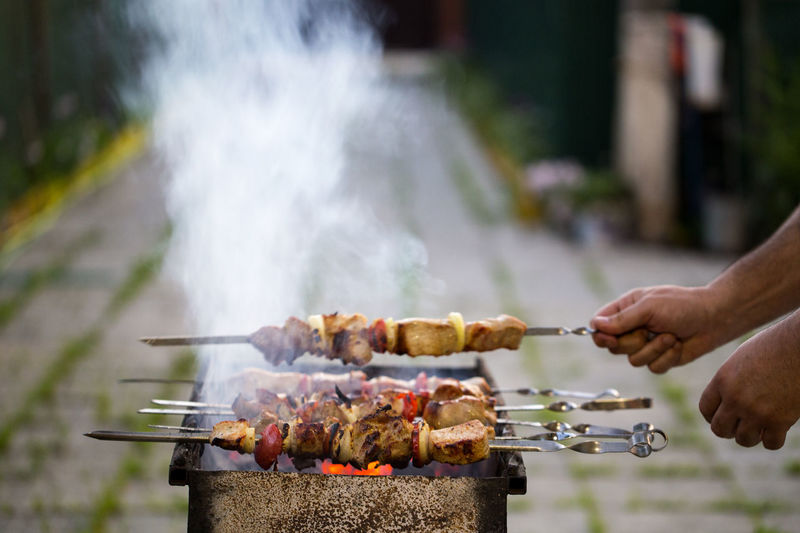 Cropped image of hands preparing food on barbecue grill in back yard
