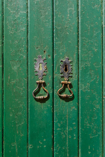 Antique door with peeling green paint, keyholes and metal rings background