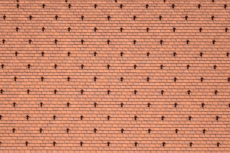 Fragment of a tiled roof of an old building in vienna. design of a red roof of made of shingles.