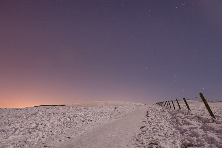 Scenic view of snowy landscape against clear sky at night