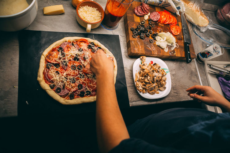 Closeup hand of chef baker in white uniform making pizza at kitchen
