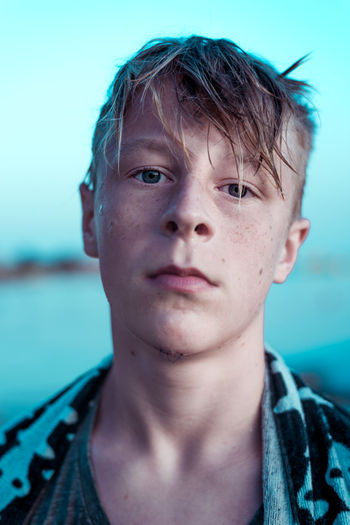 Close-up portrait of boy against blue sky