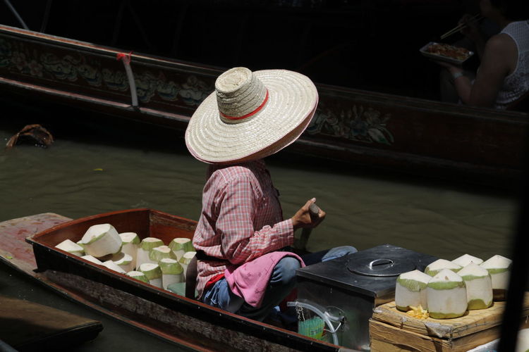 Man selling coconuts in boat at floating market