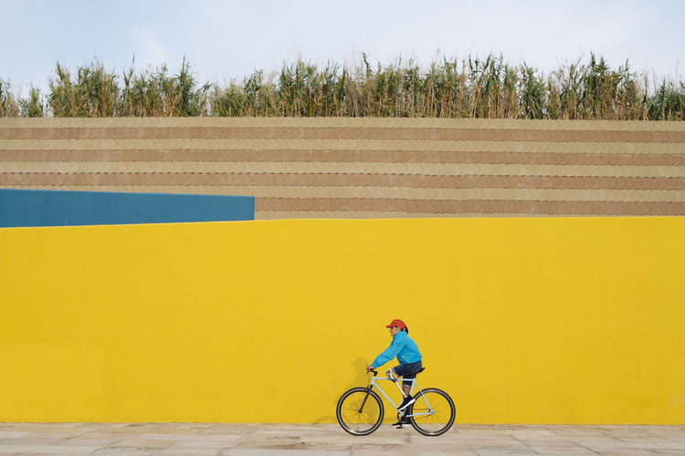 Man riding bicycle against yellow wall