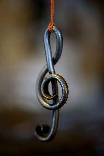A metal sheet music key hangs in a rope in a blacksmith's workshop