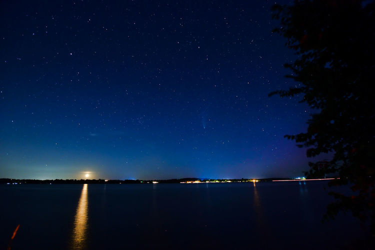 Scenic view of lake against sky at night with comet neowise
