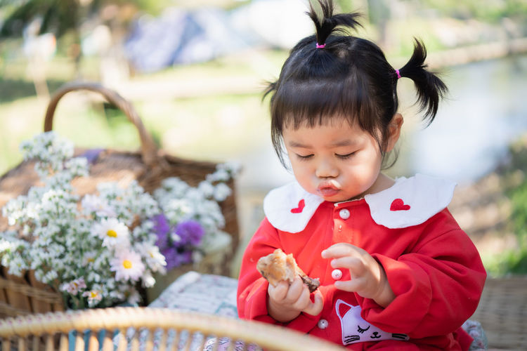 Cute girl holding food while sitting at park