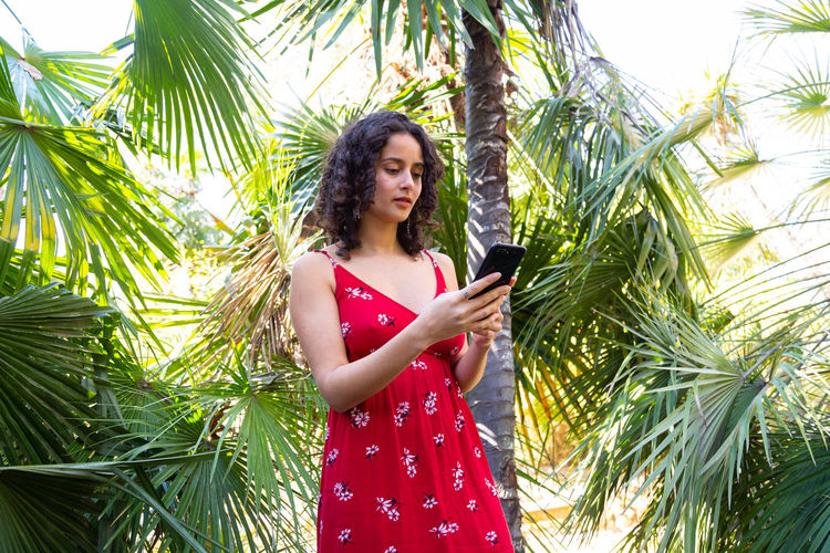 Young woman standing against plants