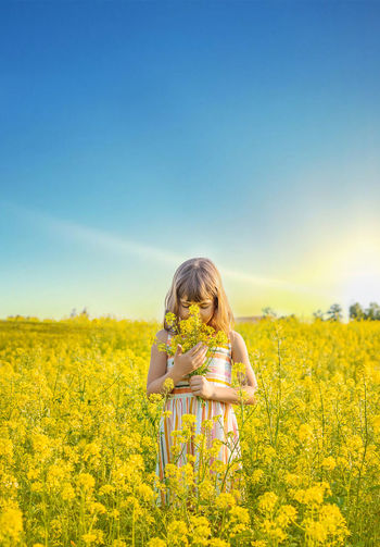 Girl with flowers standing in field