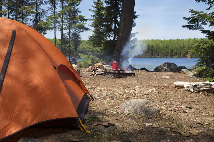 Orange tent and campfire on lake in the boundary waters canoe area wilderness of northern  minnesota