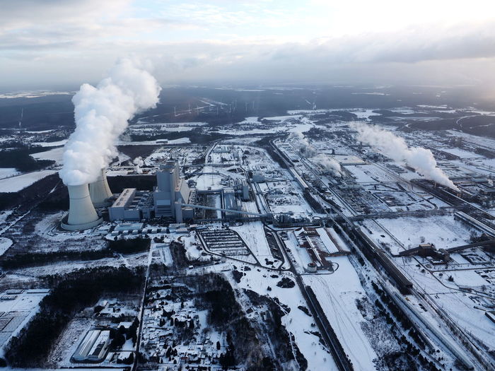 Aerial view of frozen lake against sky during winter with coal-fire power station