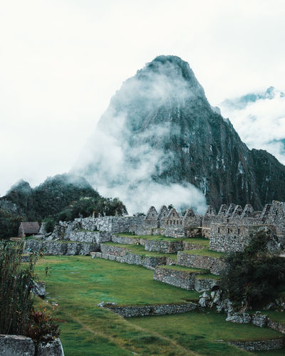 Old ruins of machu picchu against mountains during foggy weather