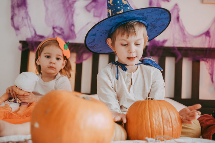 Two little kids in festive halloween costumes with pumpkins having fun. family 