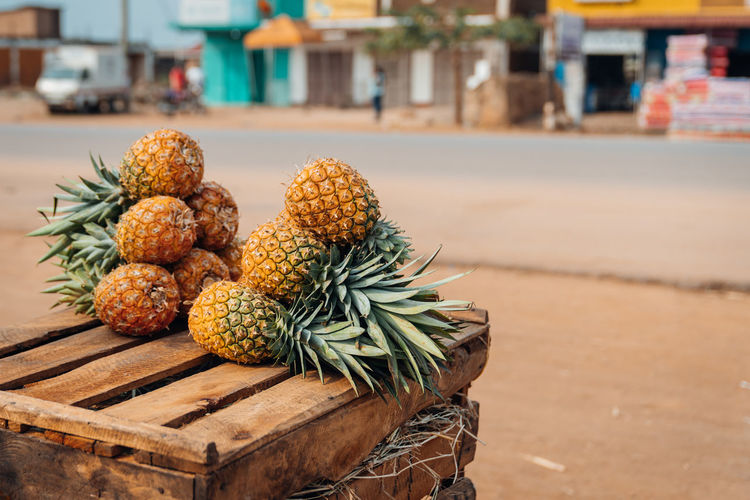 Pineapples on a wooden box or chest. ugandan street in the background.