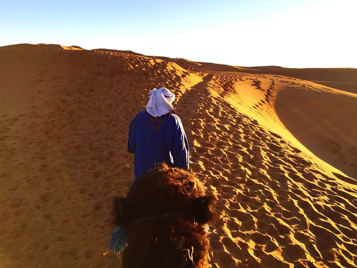 Rear view of boy standing in desert against sky