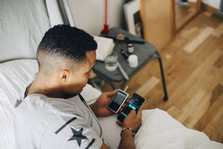 Man using mobile phone on bed at home
