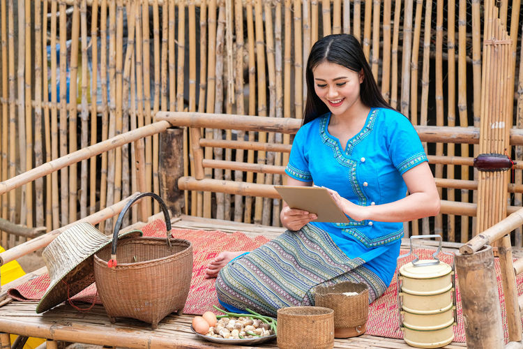 Smiling young woman using digital tablet while sitting outdoors
