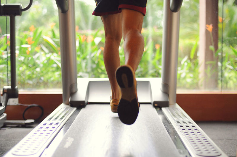 Low section of man running on treadmill at gym