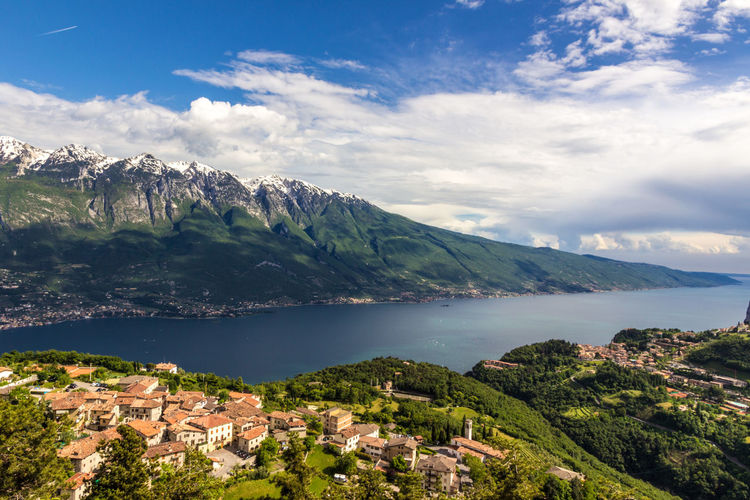 View of townscape by sea and mountains against sky