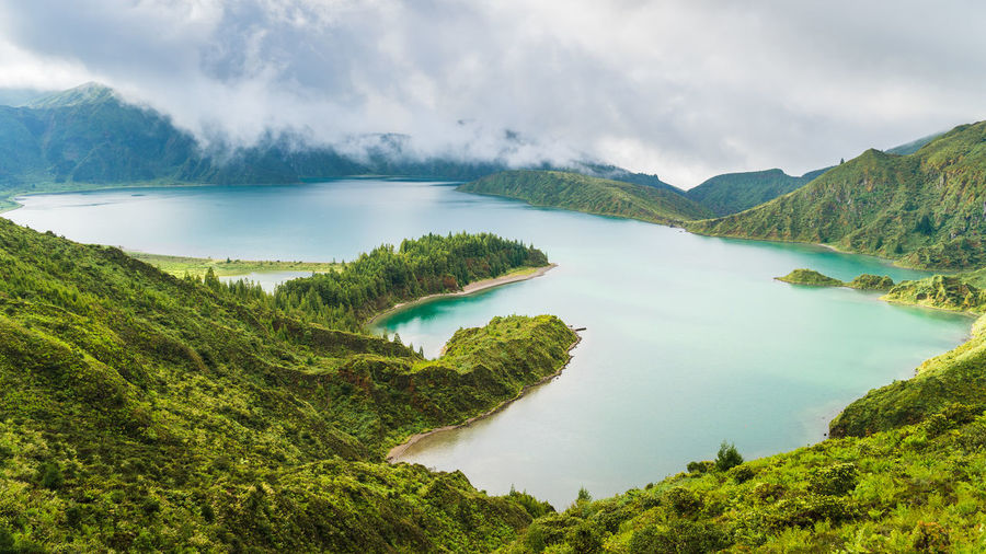 Scenic view of lake amidst mountains against cloudy sky