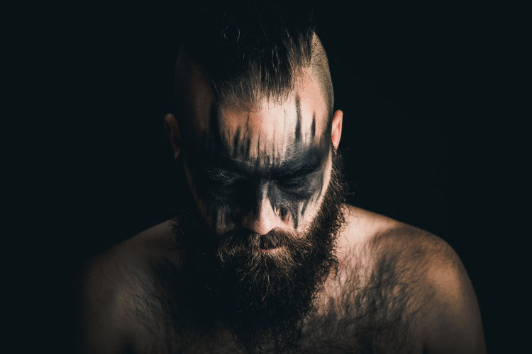 Portrait of shirtless, viking warrior against black background