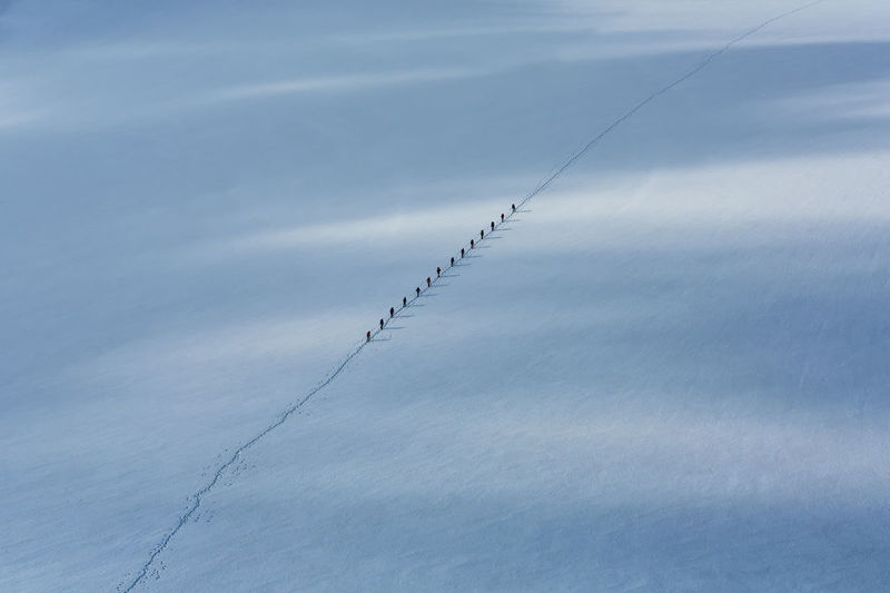 High angle view of people walking in row on snow during winter