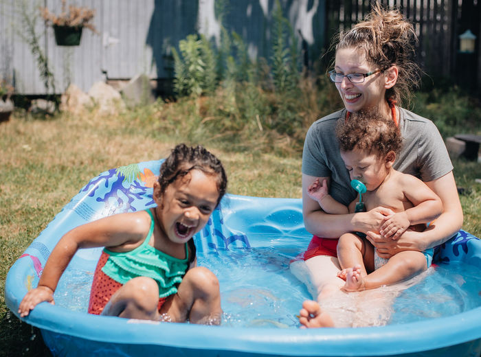 Cheerful mother with kids relaxing in wading pool