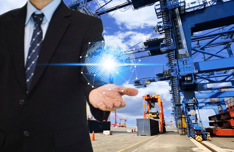 Digital composite image of businessman holding globe icon at shipping yard