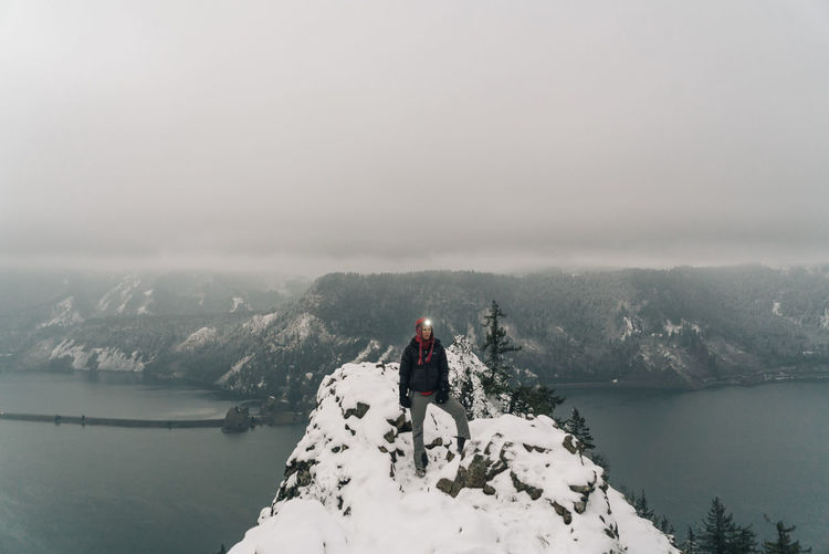 A young woman stands on the top of a snowy point in the columbia gorge
